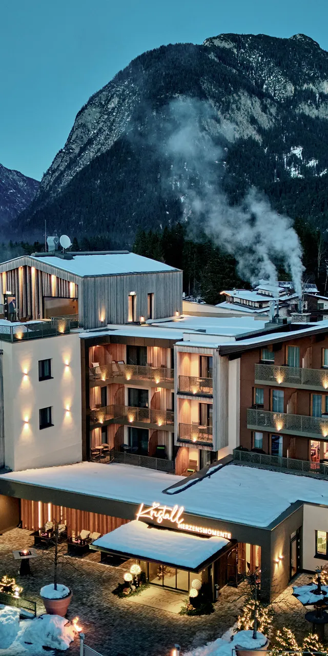 Luxury hotel Kristall in snow-covered alpine village at twilight with mountain backdrop