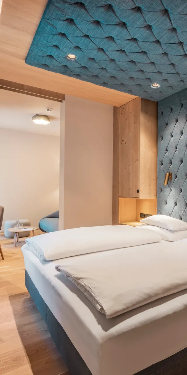 Modern hotel room with double bed, wood accents, and padded blue wall design