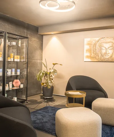 Moderner Spa-Wartebereich mit gemütlicher Sitzgruppe, LED-Deckenleuchte und Hautpflegeprodukten