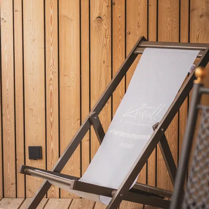 Wooden patio with a canvas deck chair printed with hashtag herzensmomente