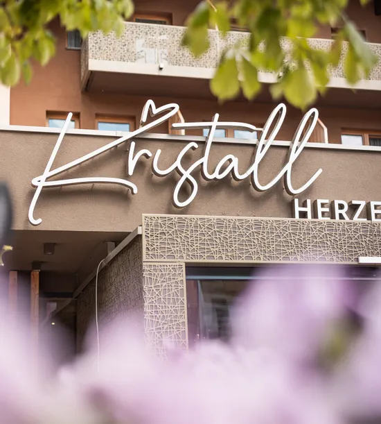 Hoteleingang Kristall mit moderner Fassade und Blumen im Vordergrund