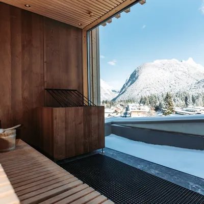 Moderne Holzsauna mit Bergblick und verschneitem Dorf im Außenbereich
