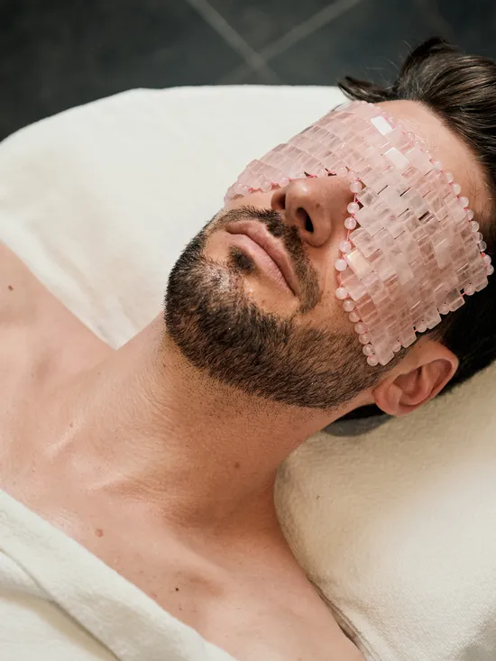 Mann entspannt mit Rosenquarz-Augenmaske während einer Spa-Behandlung
