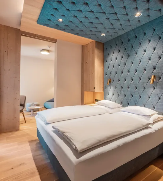 Modern hotel room with double bed, wood accents, and padded blue wall design