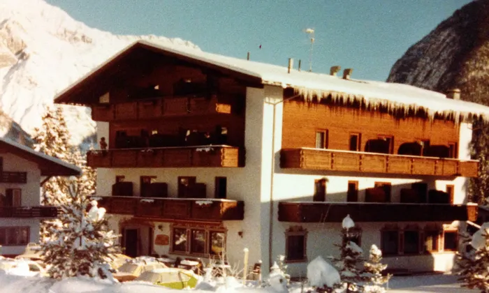 Alpine ski lodge with wooden balconies and snow-covered roof in mountain setting