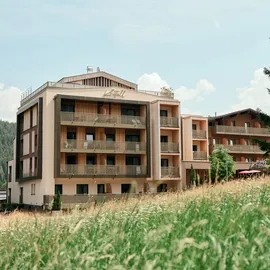 Modern mountain hotel Kristall with balconies, surrounded by trees and meadow