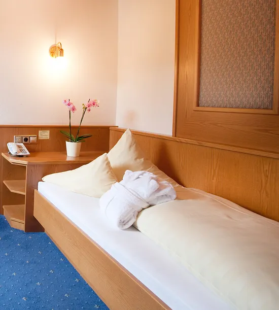 Gemütliches Einzelzimmer im Hotel mit Holzmöbeln, Schreibtisch, Bett und Badezimmer