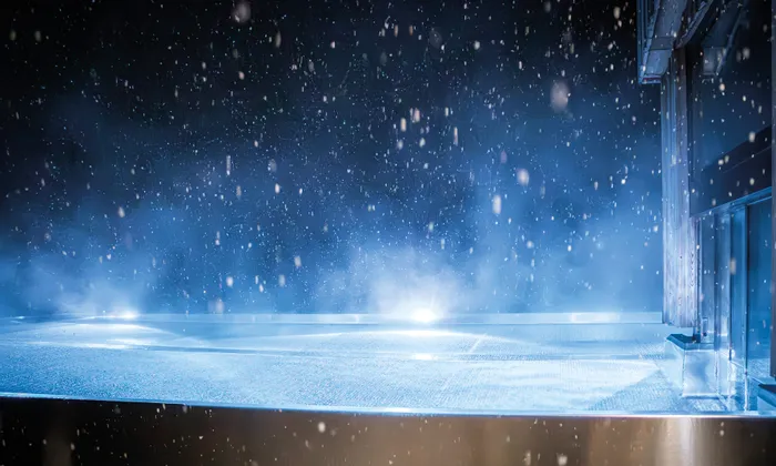 Outdoor rooftop infinity pool at night with snowfall and glowing lights