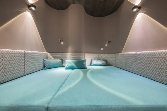 Modern spa relaxation lounge with turquoise cushions and soft wall lighting