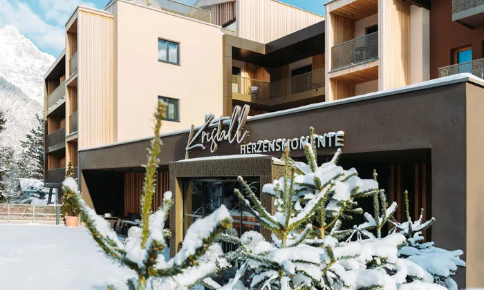 Modernes Alpenhotel Kristall mit schneebedeckten Tannen und Bergkulisse