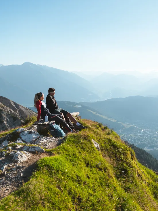 Wanderer entspannen auf Bank mit Blick auf alpines Tal und Berglandschaft