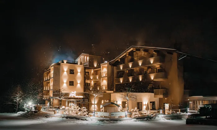 Luxury mountain hotel with warm lights surrounded by snow at night