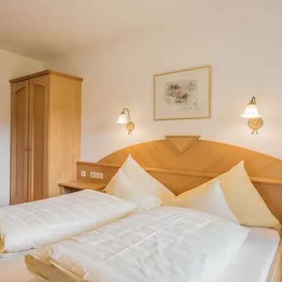 Helles Hotelzimmer mit Doppelbett, Holzmöbeln, Fernseher und privatem Badezimmer