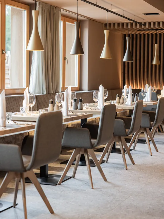 Modern restaurant interior with wooden tables, grey chairs, and elegant pendant lighting